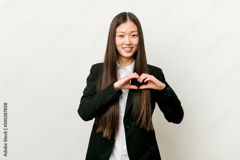 Young pretty chinese business woman smiling and showing a heart shape with hands. Young pretty chinese business woman smiling and showing a heart shape with hands.