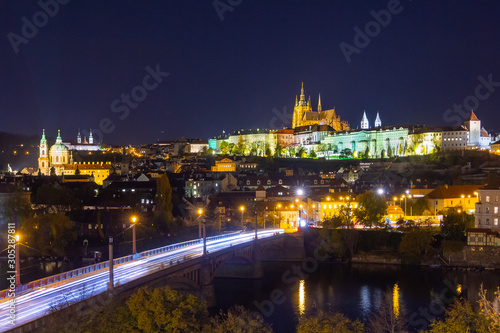 Colorful Prague Castle above the River Vltava at night. Cityscape with car light trails.