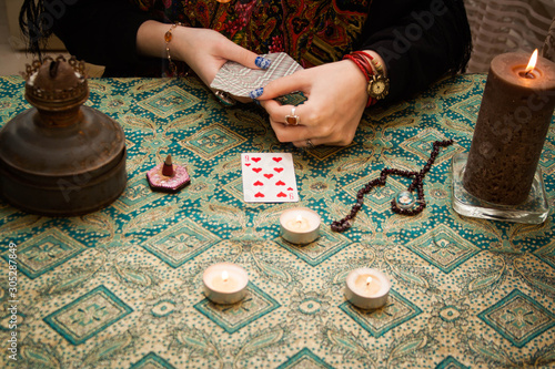 Gypsy fortune girl stands near the table with magical attributes: candles, cards, bahurs and etc.
