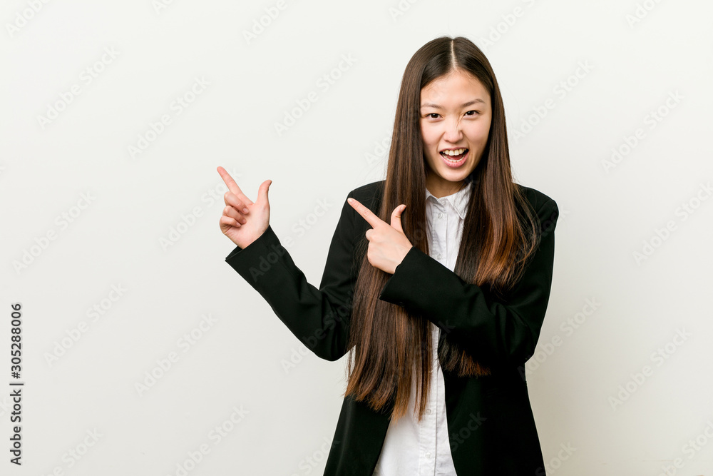 Young pretty chinese business woman pointing with forefingers to a copy space, expressing excitement and desire. Young pretty chinese business woman pointing with forefingers to a copy space, expressing excitement and desire.