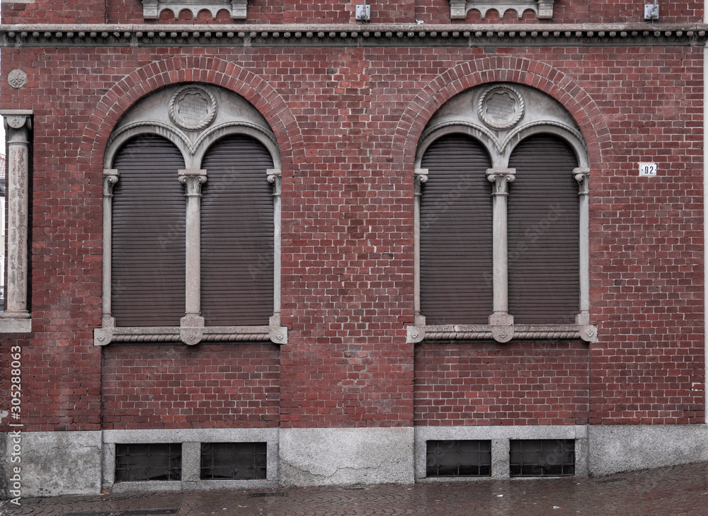 brick facade with mullioned window framed by a second arch in which a coat of arms has been inserted