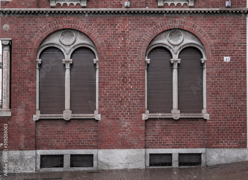 brick facade with mullioned window framed by a second arch in which a coat of arms has been inserted