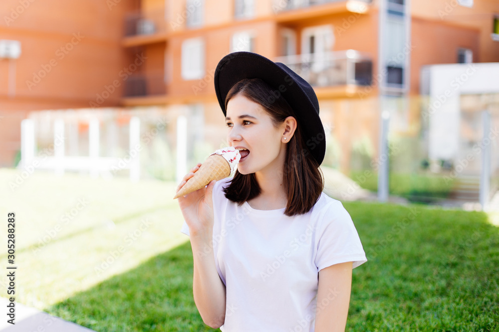 Fototapeta premium Young woman in hat enjoy ice cream on the street