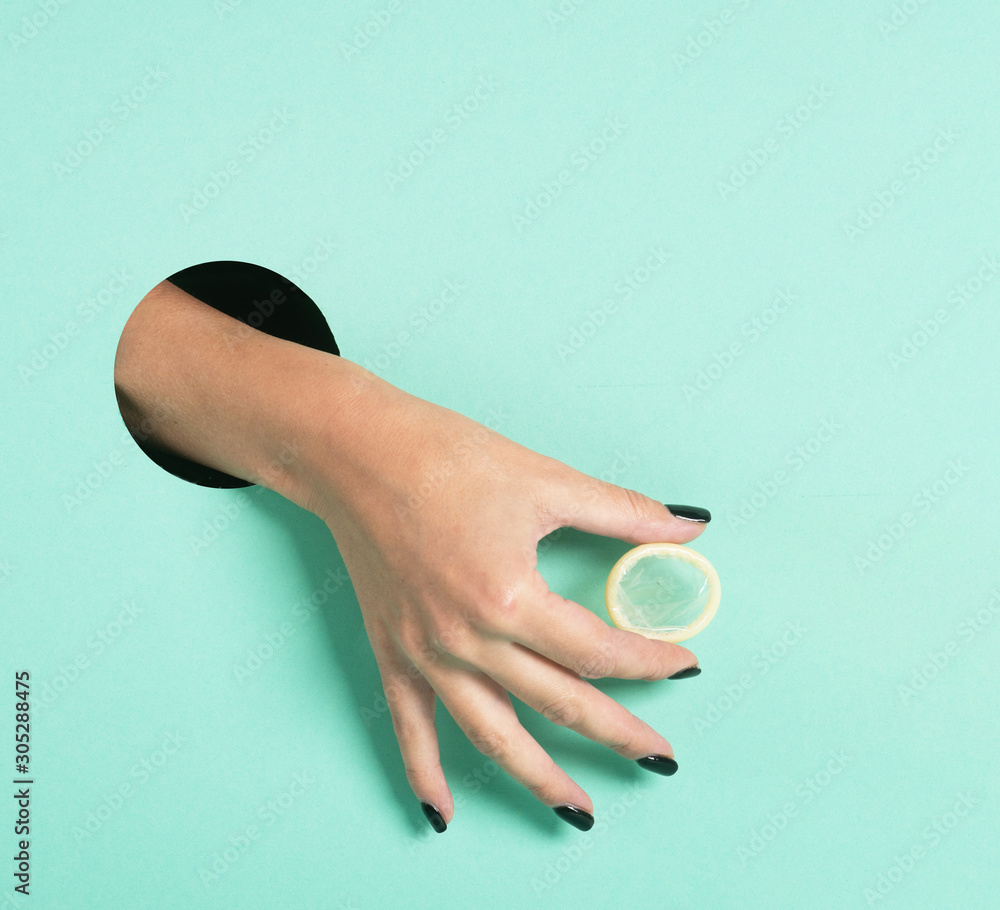 Female hands hold condom through a hole on neon mint background. Safe  anonymous sex concept. Stock Photo | Adobe Stock