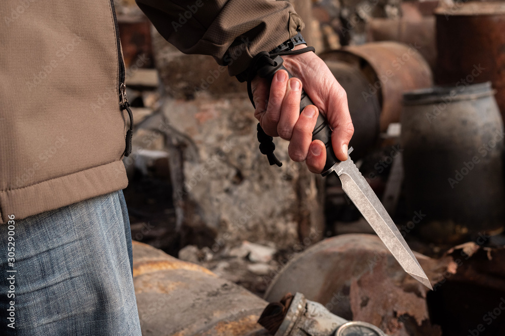 A man holds a knife in his hand. Big bayonet knife in the hand. A man holds a knife in his hand. Big bayonet knife in the hand.
