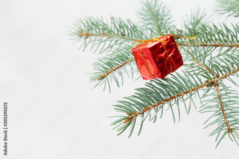 Merry christmas and a happy new year! The atmosphere of the winter holidays. Green spruce branch with decorations on a light background and free space for an inscription. Merry christmas and a happy new year! The atmosphere of the winter holidays. Green spruce branch with decorations on a light background and free space for an inscription.