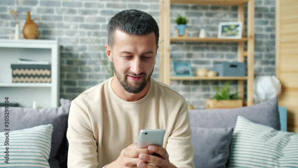 Carefree middle-aged guy is chatting online texting having fun at home alone enjoying communication. Modern devices, happiness and lifestyle concept.
