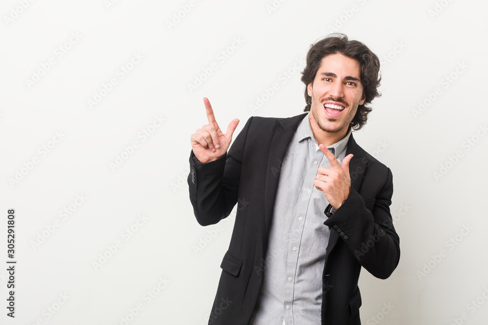 Young business man against a white background pointing with forefingers to a copy space, expressing excitement and desire. Young business man against a white background pointing with forefingers to a copy space, expressing excitement and desire.