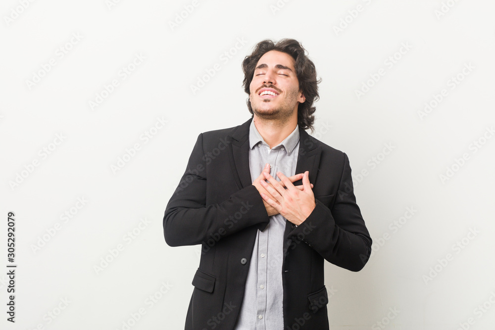 Young business man against a white background laughing keeping hands on heart, concept of happiness. Young business man against a white background laughing keeping hands on heart, concept of happiness.