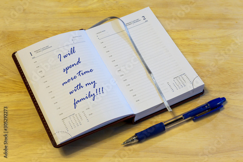 The diary is on the table. The diary is open on the first of January page. On the page it is written: "I will spend more time with my family!!!".