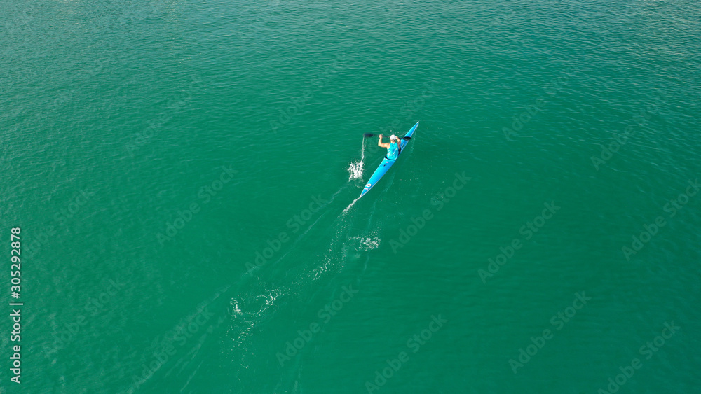 Aerial drone top down photo of kayak athlete competing in tropical exotic lake with green water