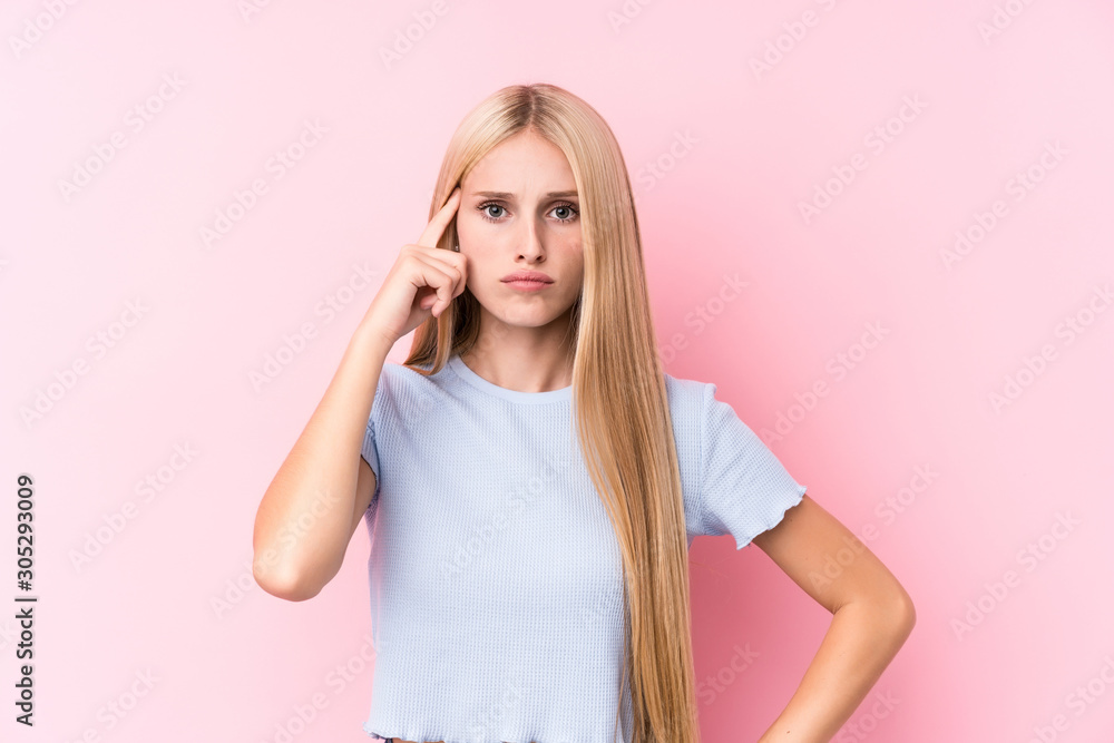 Young blonde woman on pink background pointing temple with finger, thinking, focused on a task. Young blonde woman on pink background pointing temple with finger, thinking, focused on a task.