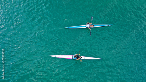 Aerial drone top down photo of fit women competing in sport canoe in tropical exotic lake with emerald waters