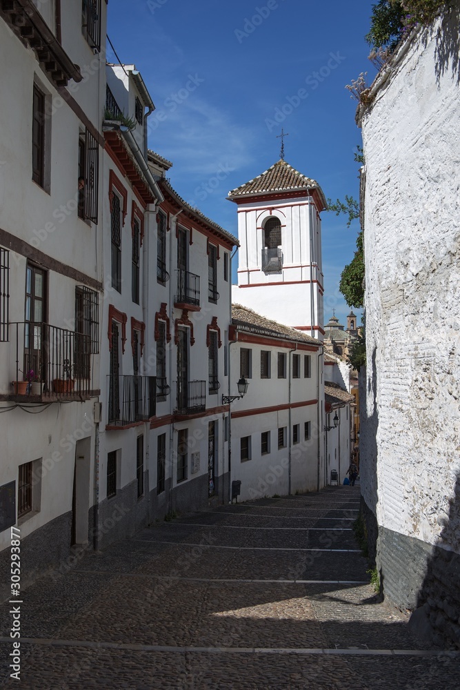 Narrow street and a church in Albaicin district of Granada, Spain
