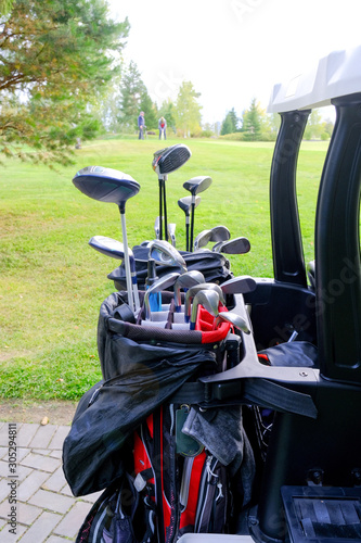 Bag with golf clubs in front of the players playing.