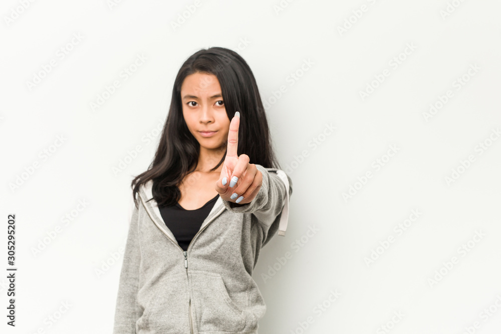 Young fitness chinese woman showing number one with finger. Young fitness chinese woman showing number one with finger.