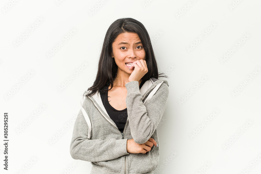 Young fitness chinese woman biting fingernails, nervous and very anxious. Young fitness chinese woman biting fingernails, nervous and very anxious.