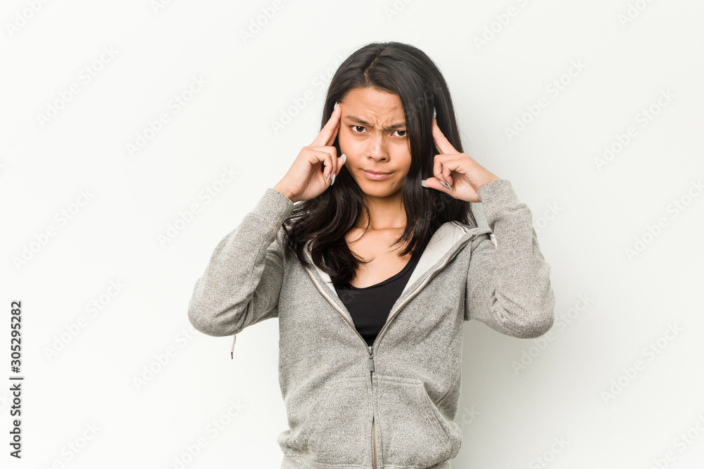 Young fitness chinese woman focused on a task, keeping forefingers pointing head. Young fitness chinese woman focused on a task, keeping forefingers pointing head.