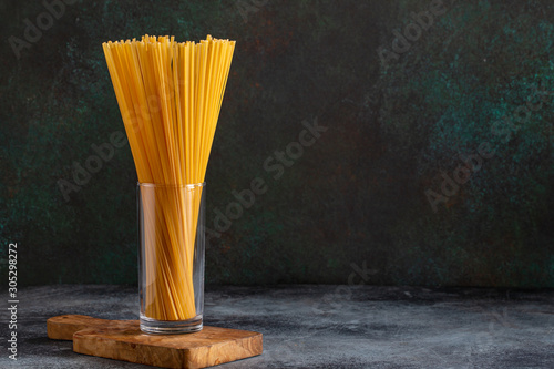 Obraz na plátně Raw spaghetti bavette in glass on dark background with copy space
