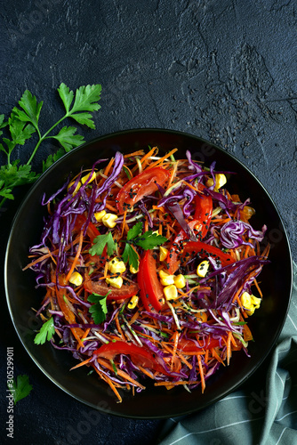 Red cabbage salad cole slaw with carrot and cucumber in a bow. Top view.