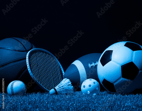 Sports equipment, rackets and balls on green grass with black background and copy space..