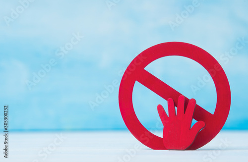 Red forbidden sign and hand  on blue background.