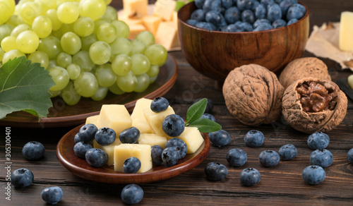 blueberry grapes and cheese on a wooden background