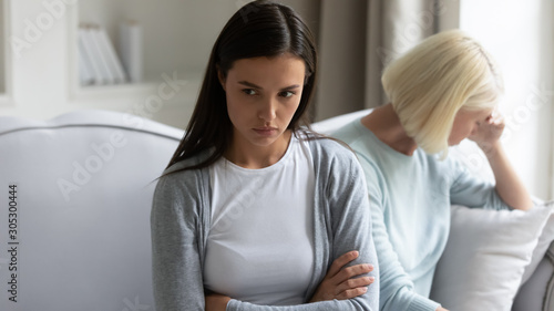 Being in quarrel adult daughter sitting separately from elderly mother