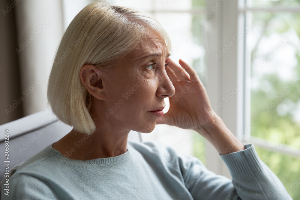 Elderly woman looking out the window feels lonely Elderly woman looking out the window feels lonely
