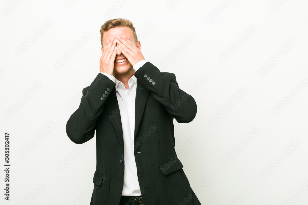 Young caucasian business man covers eyes with hands, smiles broadly waiting for a surprise. Young caucasian business man covers eyes with hands, smiles broadly waiting for a surprise.