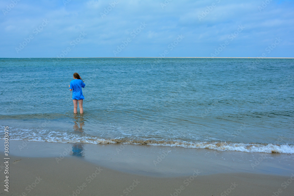 Woman  from behind, standing in the sea,  with  copy space