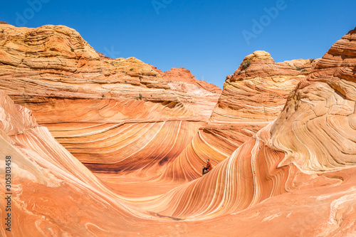 Man sitting inside the Wave feature of northern Arizona. Hiker stopping to enjoy the view and think.
