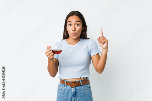 Young mixed race indian holding a tea cup having some great idea, concept of creativity.