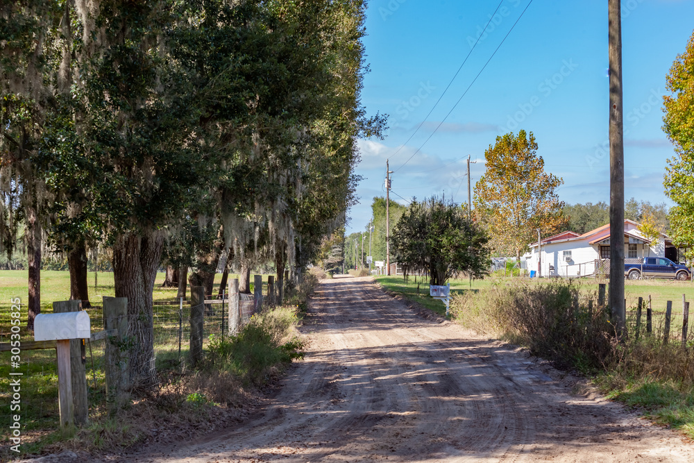 Rural driveway with tire tracks and a long wooden fence