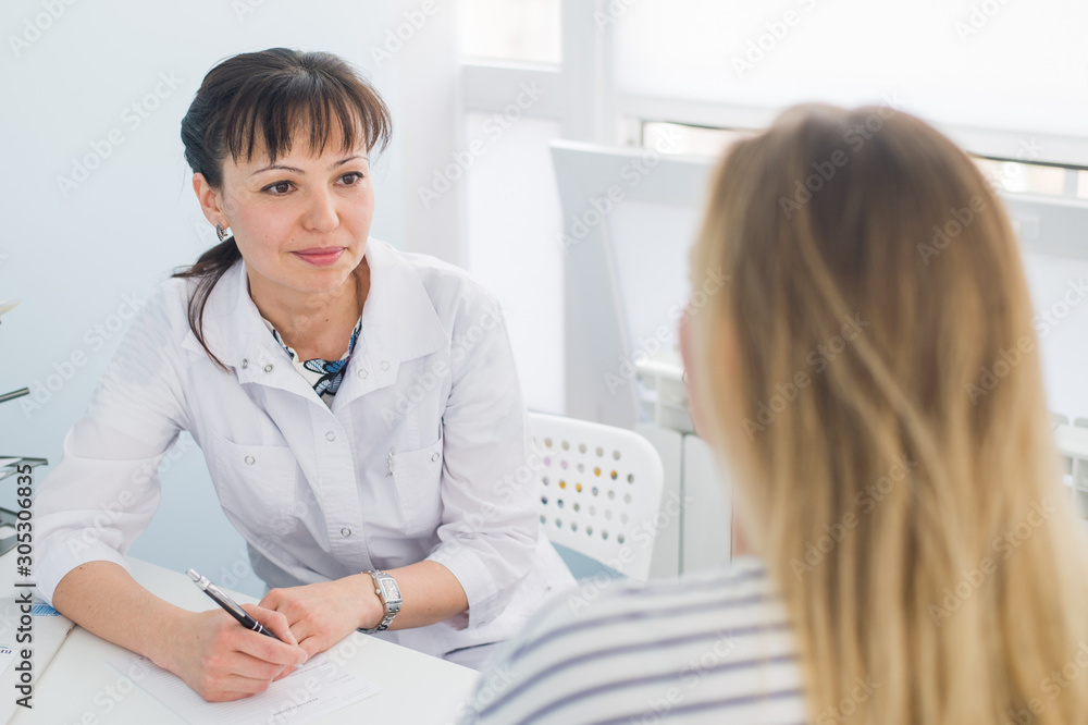 Fototapeta premium friendly female doctor comforting middle aged patient in hospital
