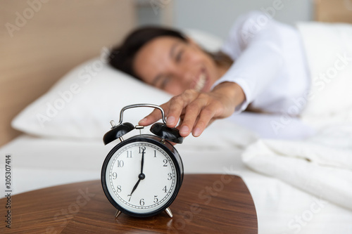 Fotografie Woman woke up at seven o'clock turns off alarm