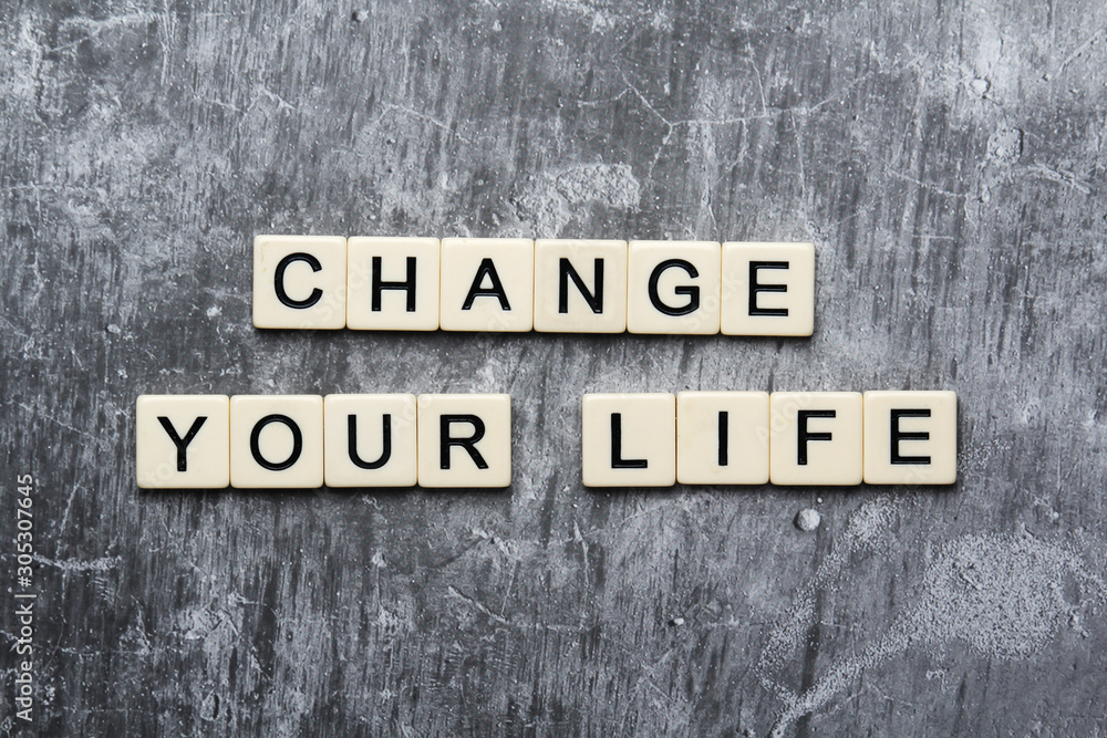 Fototapeta premium A motivational quote Change your life formed with tile letters 