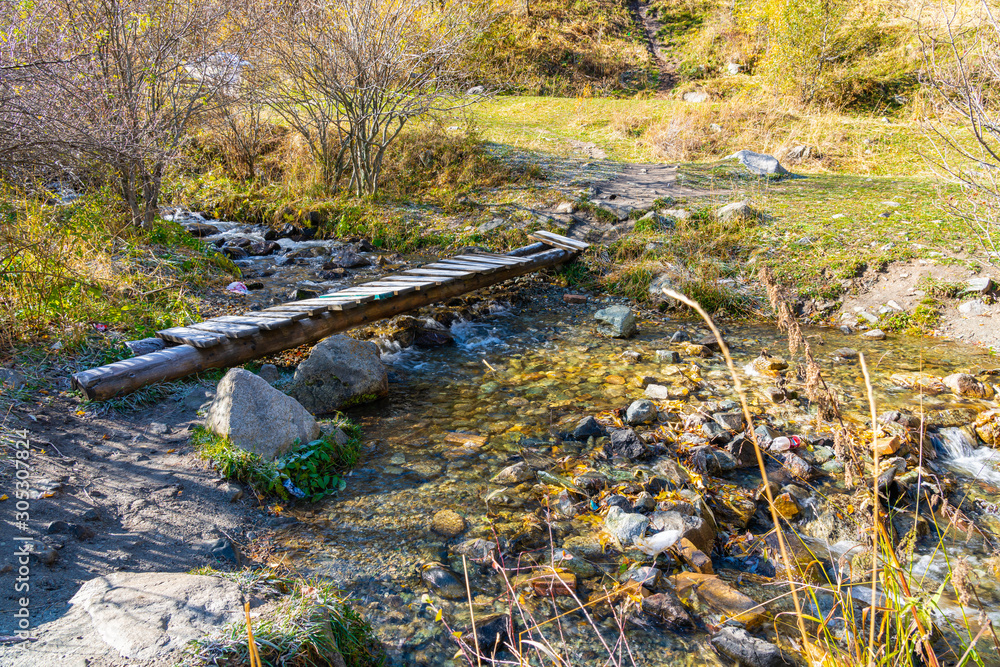 Bridge over the river in the woods. Wooden bridge over forest mountain river. Kazakhstan Bridge over the river in the woods. Wooden bridge over forest mountain river. Kazakhstan