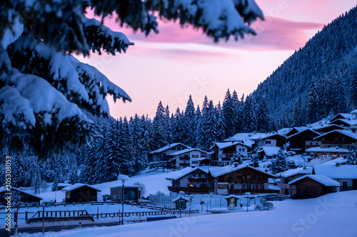 typical austrian village on a winter morning at sunrise. Snowy Winter Forest Trees and Tyrolean Houses