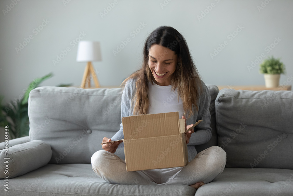 Overjoyed young woman opens box parcel feels satisfied - obrazy, fototapety, plakaty 