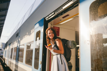 Woman peeking out train. Woman railway station. Young happy woman pulling face out train door looking for somebody railway station. Travelling. Portrait girl standing on train door when arrived