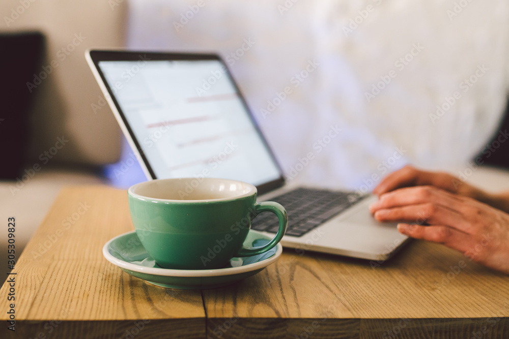 Closeup business woman hands using laptop with cup coffee. Woman Hands Typing keyboard computer In Coffee Shop. smartphone and hot cup Cappuccino in table. People lifestyles concept. Freelance theme Closeup business woman hands using laptop with cup coffee. Woman Hands Typing keyboard computer In Coffee Shop. smartphone and hot cup Cappuccino in table. People lifestyles concept. Freelance theme