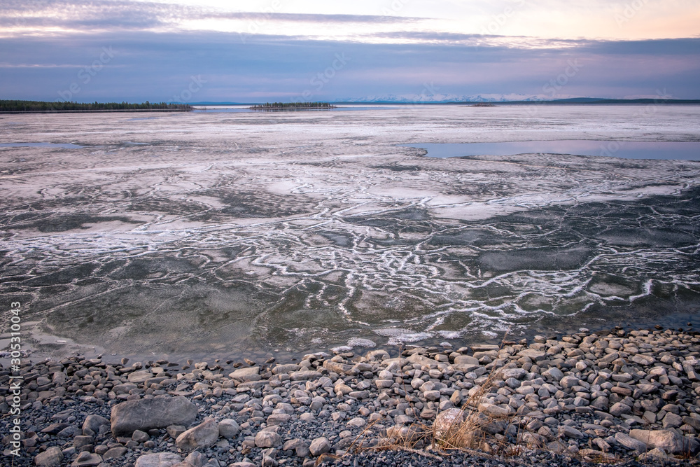 Stones on the White Sea coast at sunset. Frozen water, summer, white nights.
