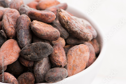 Bowl of cacao beans on a white background