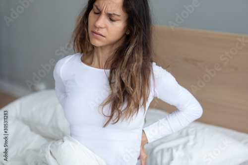 Young woman awakening feeling lower back pain