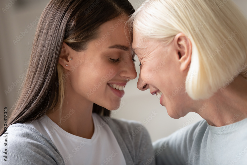 Close up faces old mother young daughter touch foreheads Close up faces old mother young daughter touch foreheads