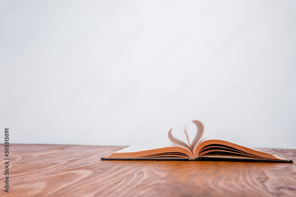 Old book and heart-shaped pages. White background. Wooden Table. text space Old book and heart-shaped pages. White background. Wooden Table. text space