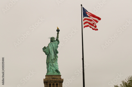 Back view of Statue of Liberty and american flag in New York, USA © Javier