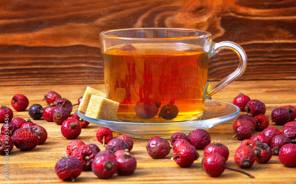 Rose hips.Dried rosehip berries with a cup of aromatic rosehip drink on a wooden background. Healing berries. Rose hips.Dried rosehip berries with a cup of aromatic rosehip drink on a wooden background. Healing berries.