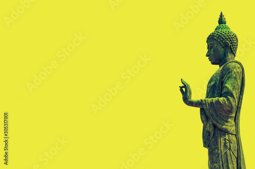 Black metal Buddha statue standing on a yellow background photo